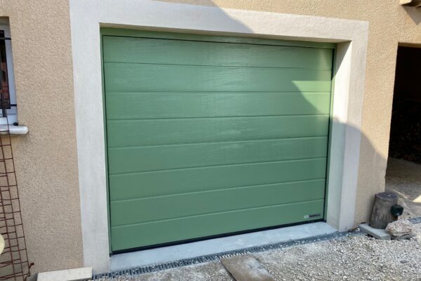 Porte de garage sectionnelle motorisée vert olive sur mesure isolée